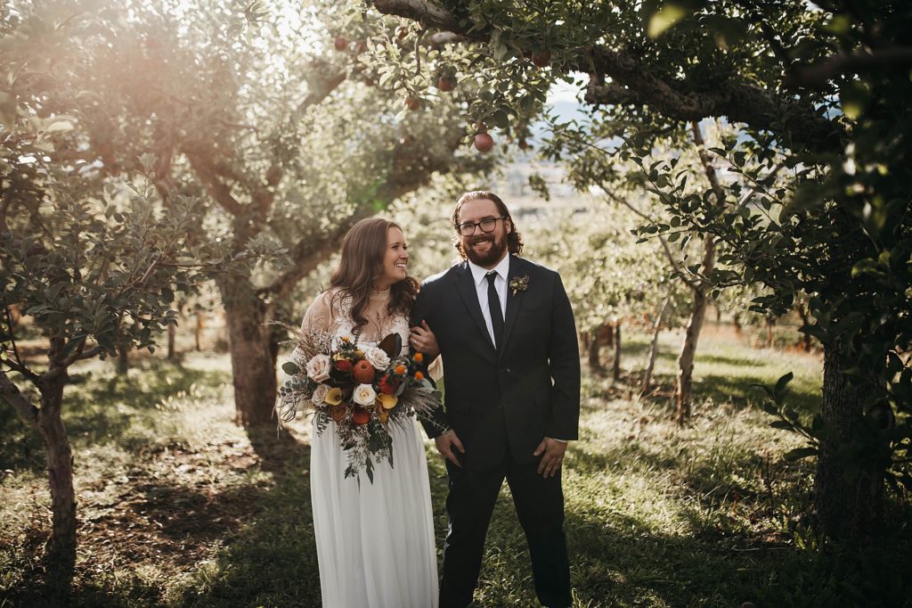 Couple smiling at the camera, bride dressed boho style, backyard elopement