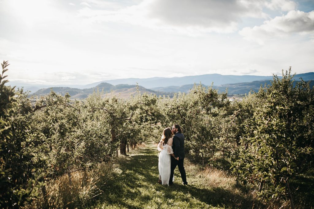 couple in wedding clothes, kissing in an Okanagan orchard